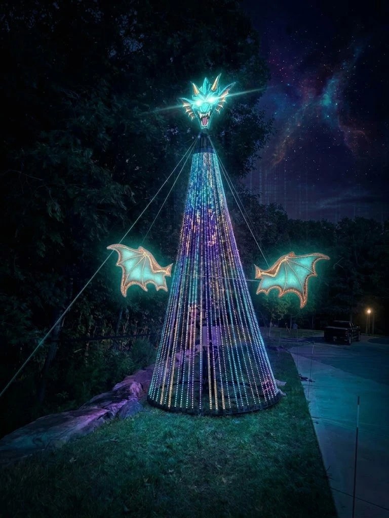 The dragon mega-tree lit at night, wings and head glowing above the driveway